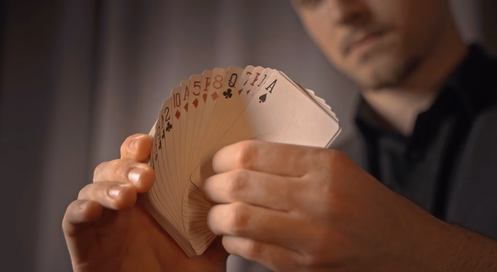 Close-up von Magier Michael Peskovs Händen, die Spielkarten fächern – Faszination im Detail für das Website Hero-Video.