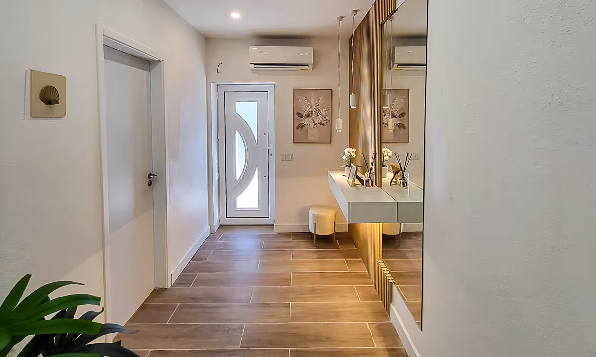 Hall de entrada moderno do apartamento Elegance I no Fundão com iluminação embutida e decoração minimalista