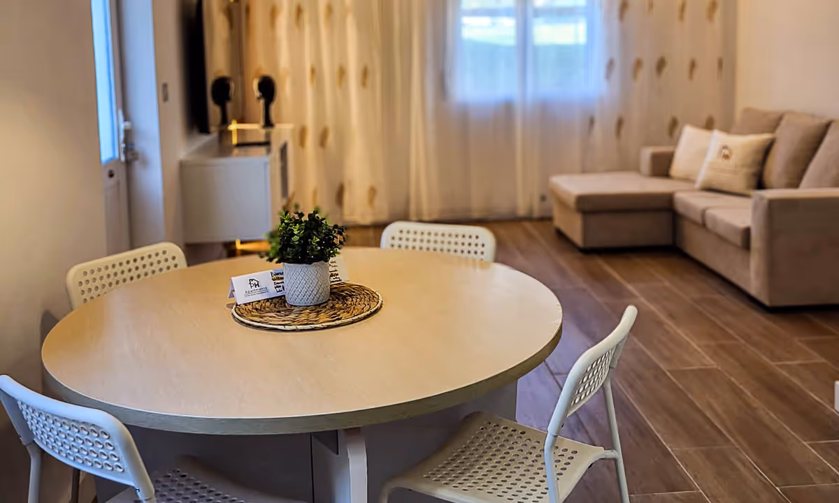 Sala de estar e jantar do apartamento Elegance I com sofá bege e cortinas translúcidas
