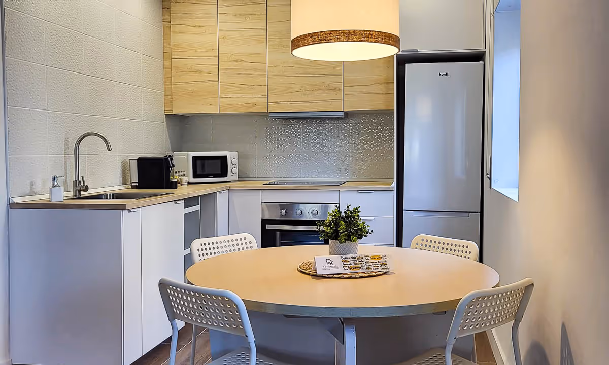 Cozinha moderna do apartamento Elegance I no Fundão com armários em madeira clara e mesa redonda