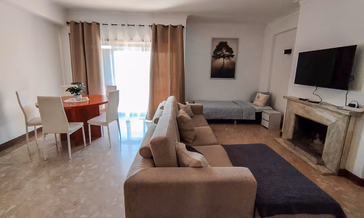 Sala de jantar e estar do apartamento Domus III com mesa redonda e cortinas bege