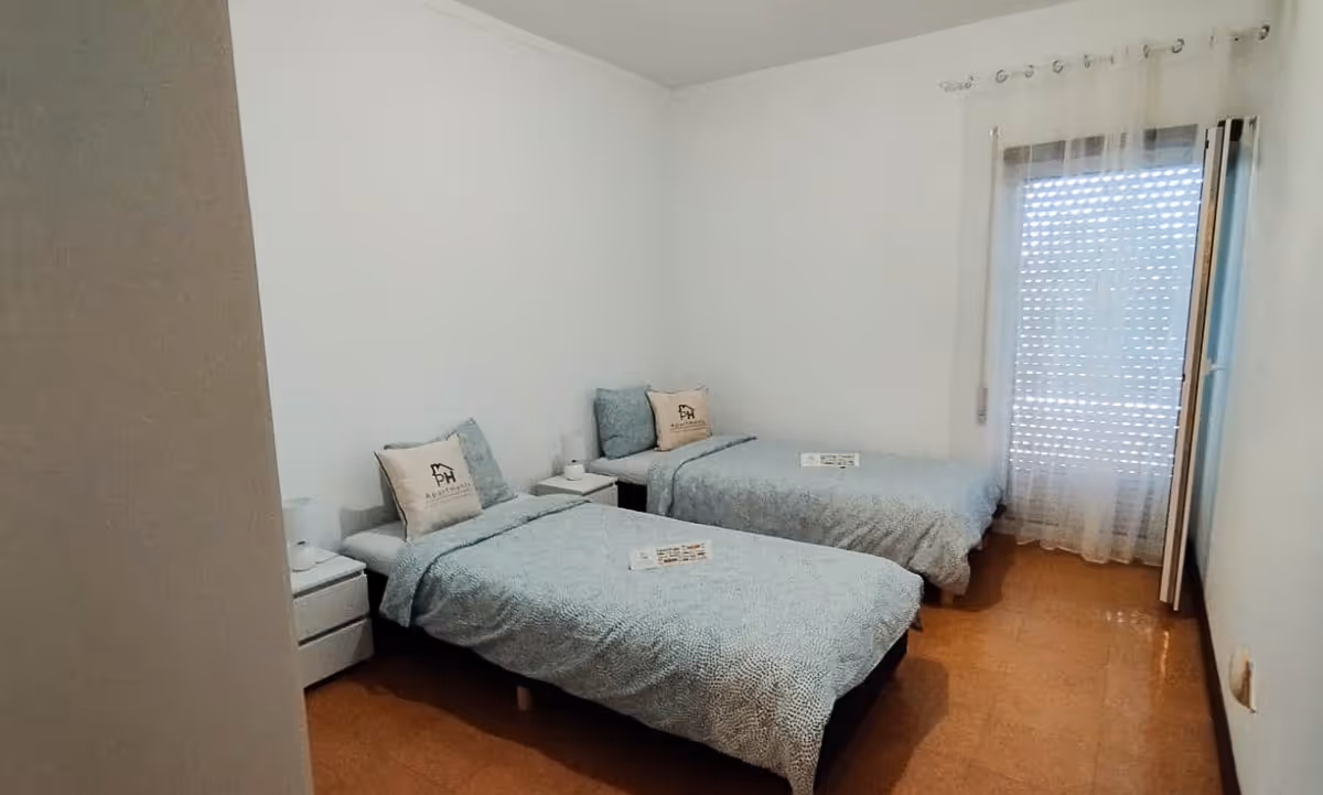 Quarto duplo do apartamento Domus III com duas camas individuais e decoração simples