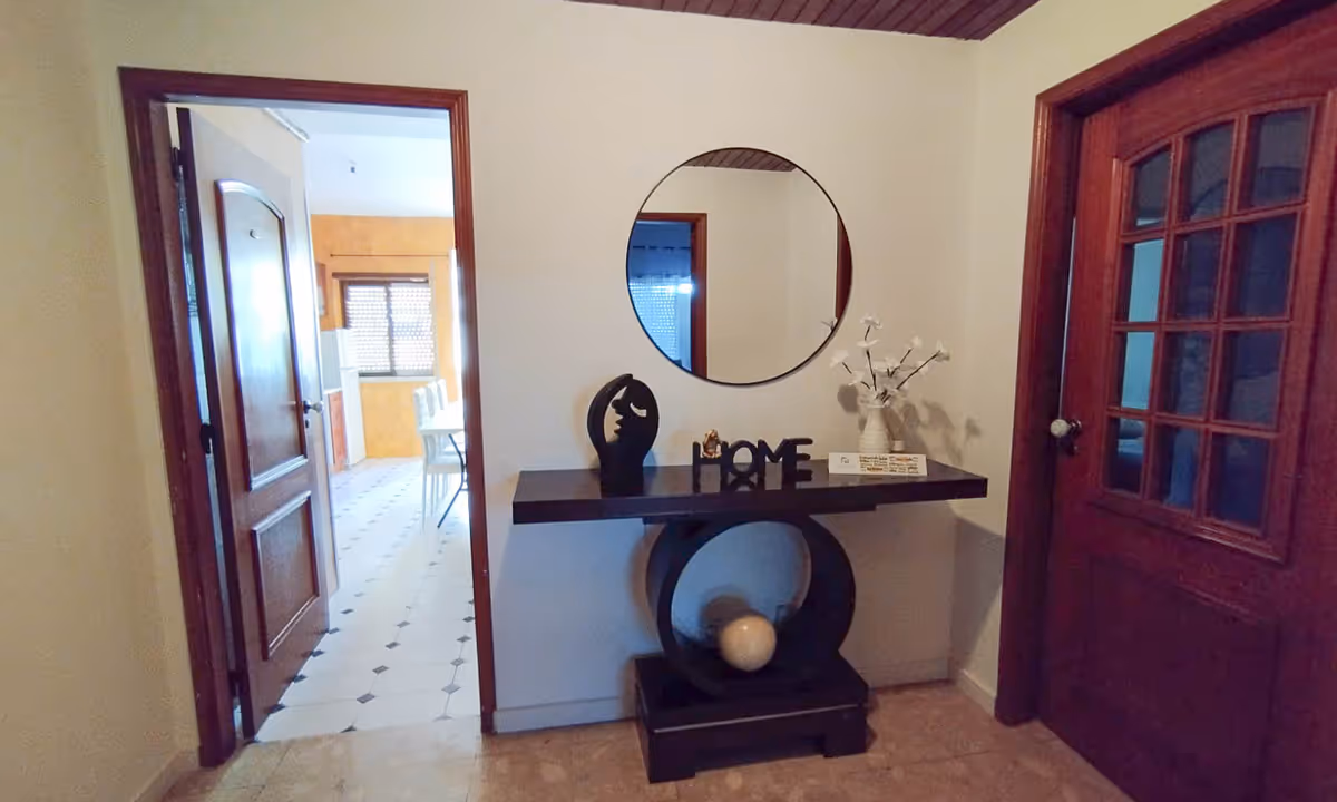 Hall de entrada do apartamento Domus III com decoração moderna e espelho redondo