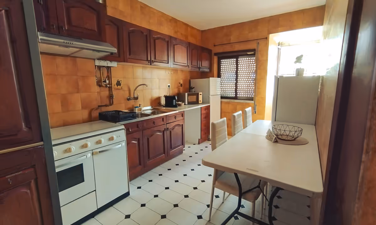 Cozinha do apartamento Domus III em Castelo Branco com armários em madeira e mesa branca