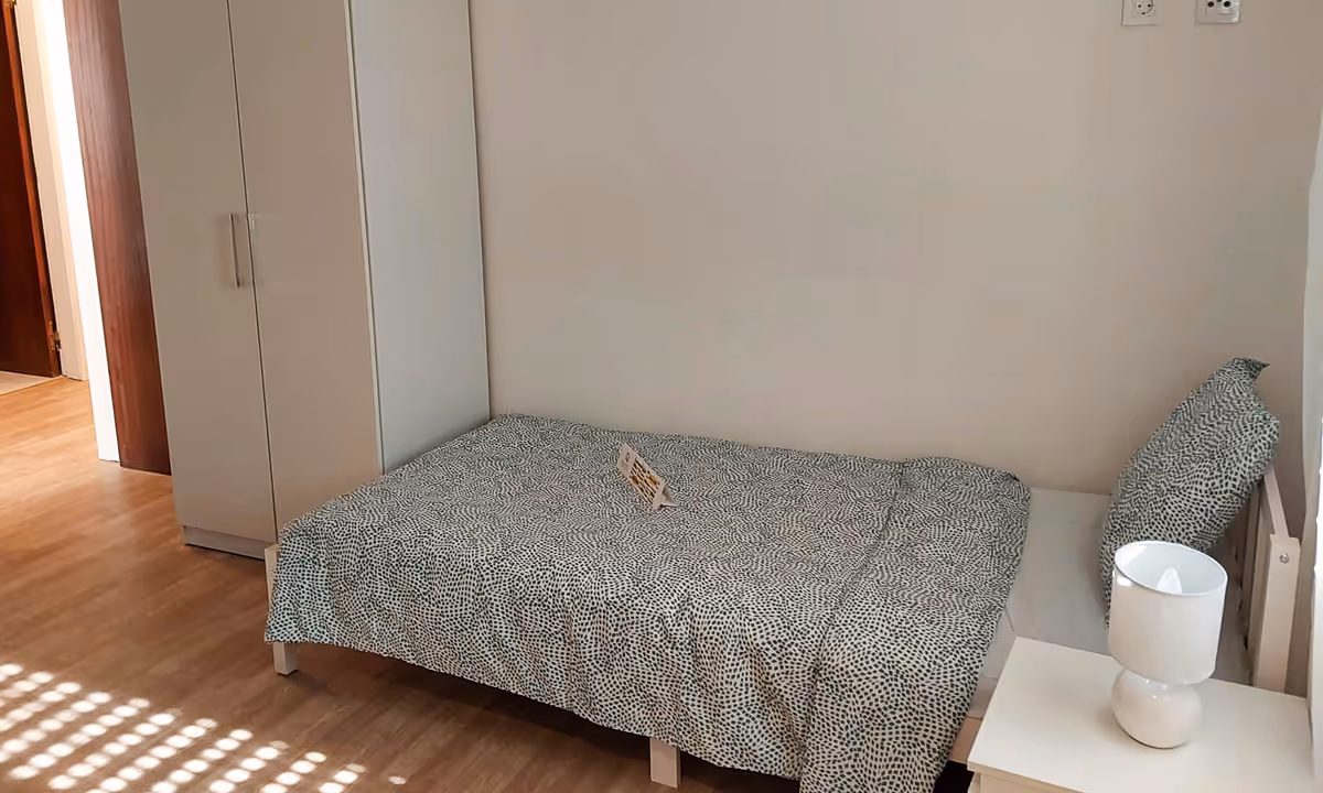 Quarto do apartamento Elegance II com cama individual, guarda-roupa e luz natural