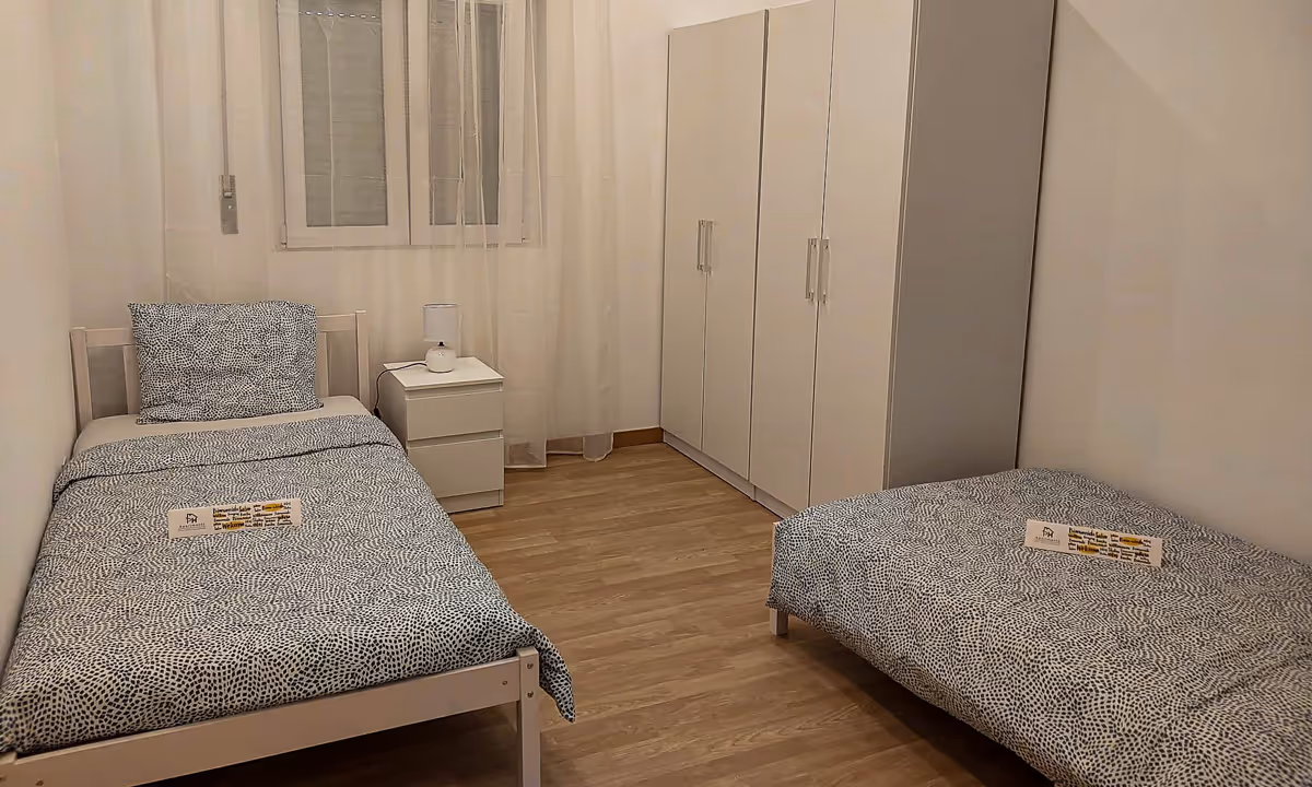 Quarto duplo do apartamento Elegance II com duas camas individuais e decoração neutra