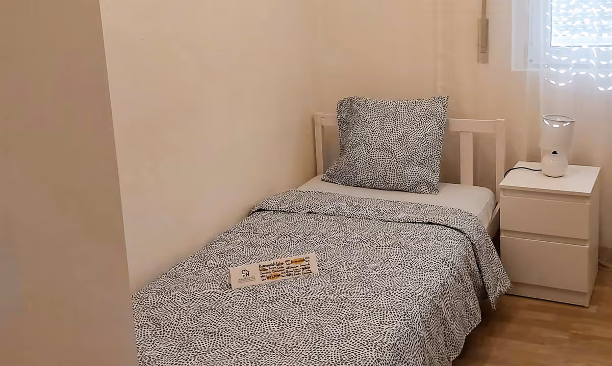 pormenor quarto duplo do apartamento Elegance II com mesa de cabeceira e candeeiro branco
