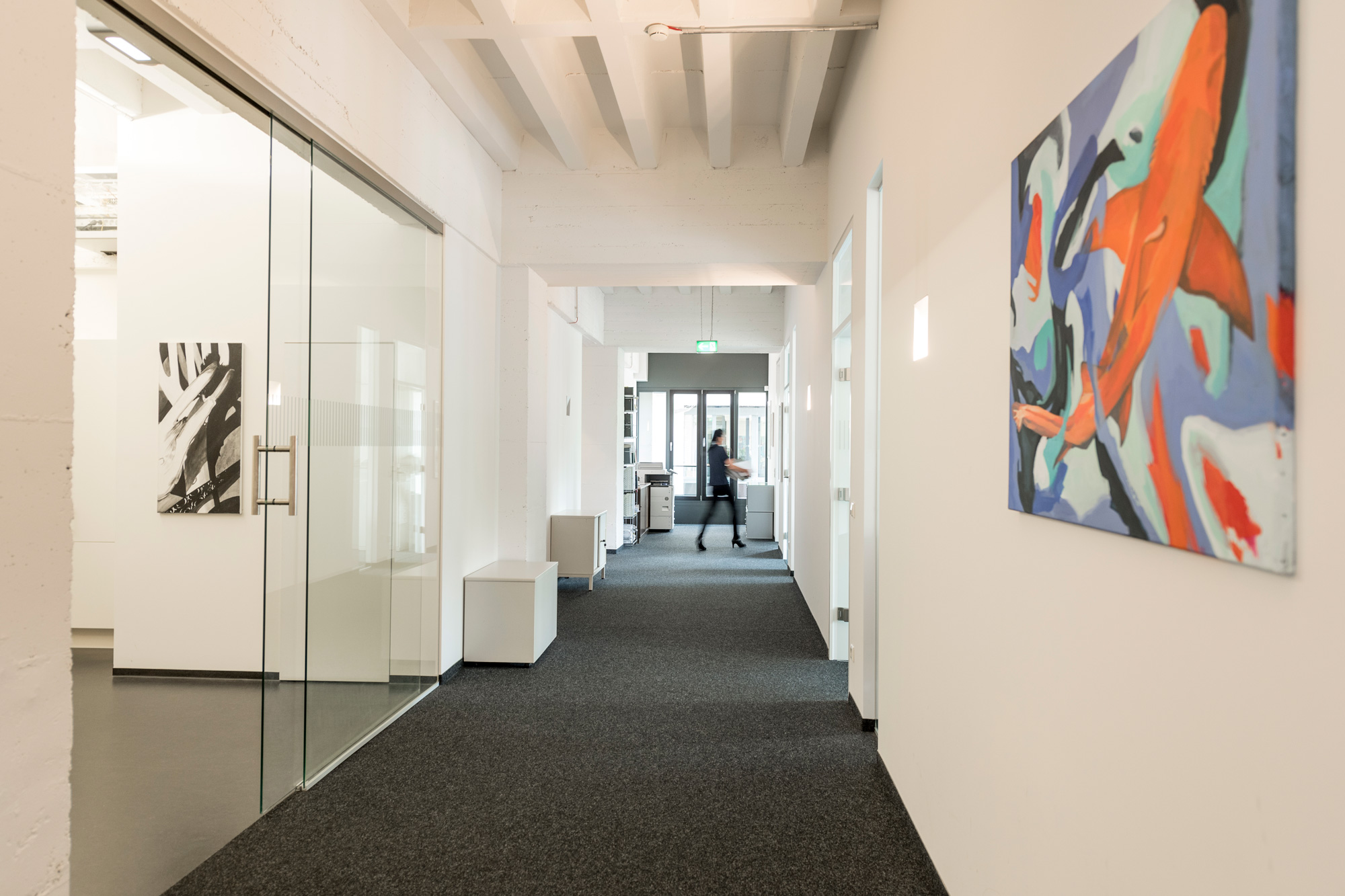 Moderner Bürogang mit abstraktem Wandbild.