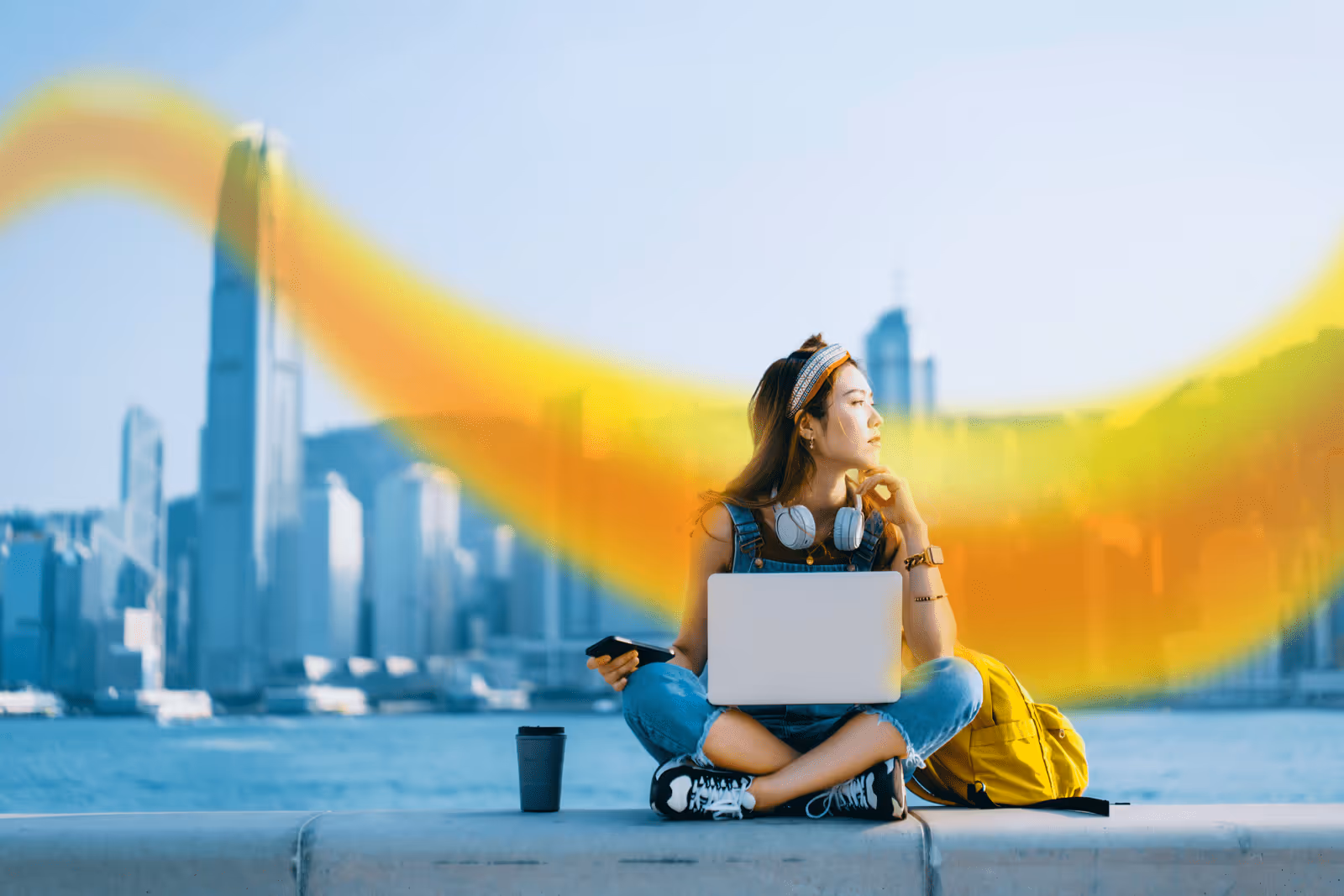 a lady sat working on a laptop outside in a city