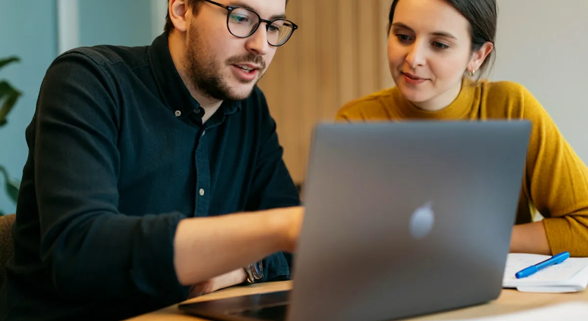 2 people going through a demo on a laptop