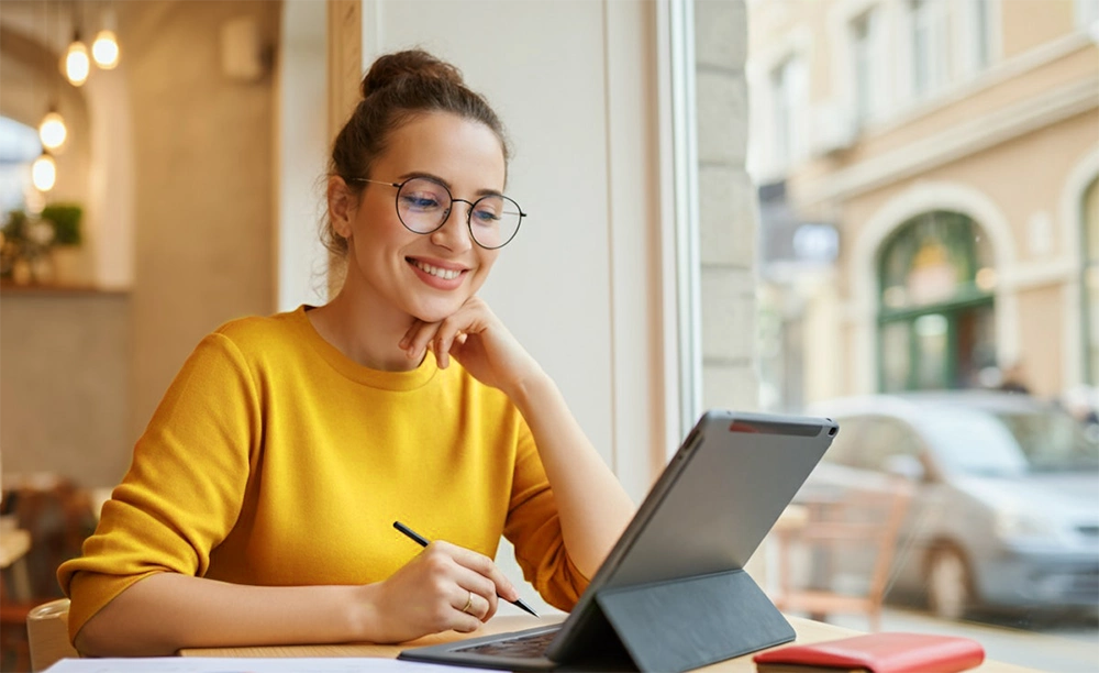 person writing in front of a laptop