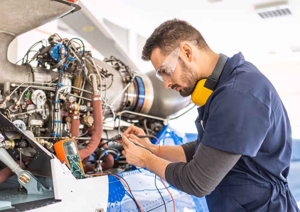 An aircraft engineer with electrical tester working on an aircraft engine