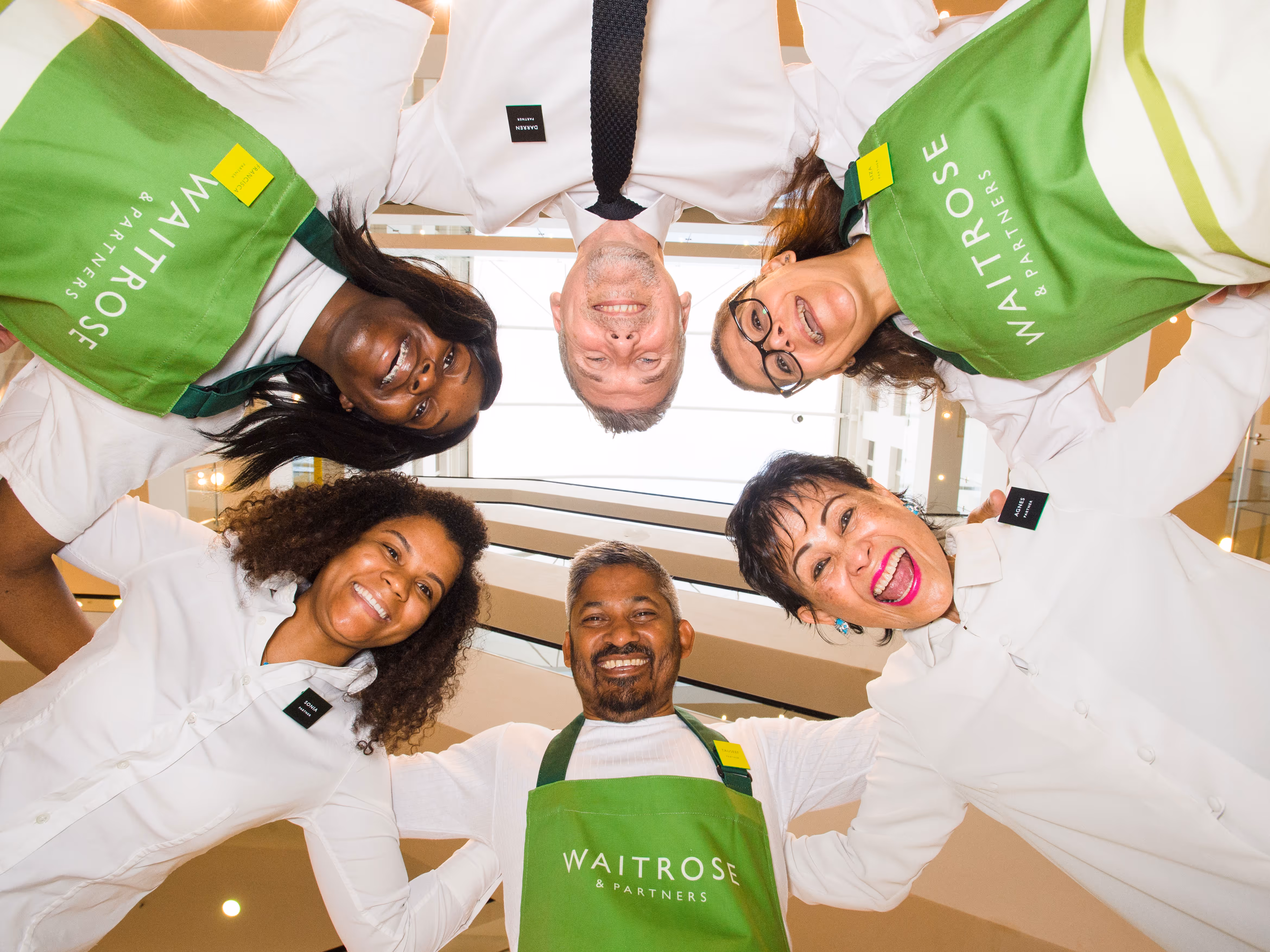 John Lewis and Partners employees leaning in looking down at the camera smiling
