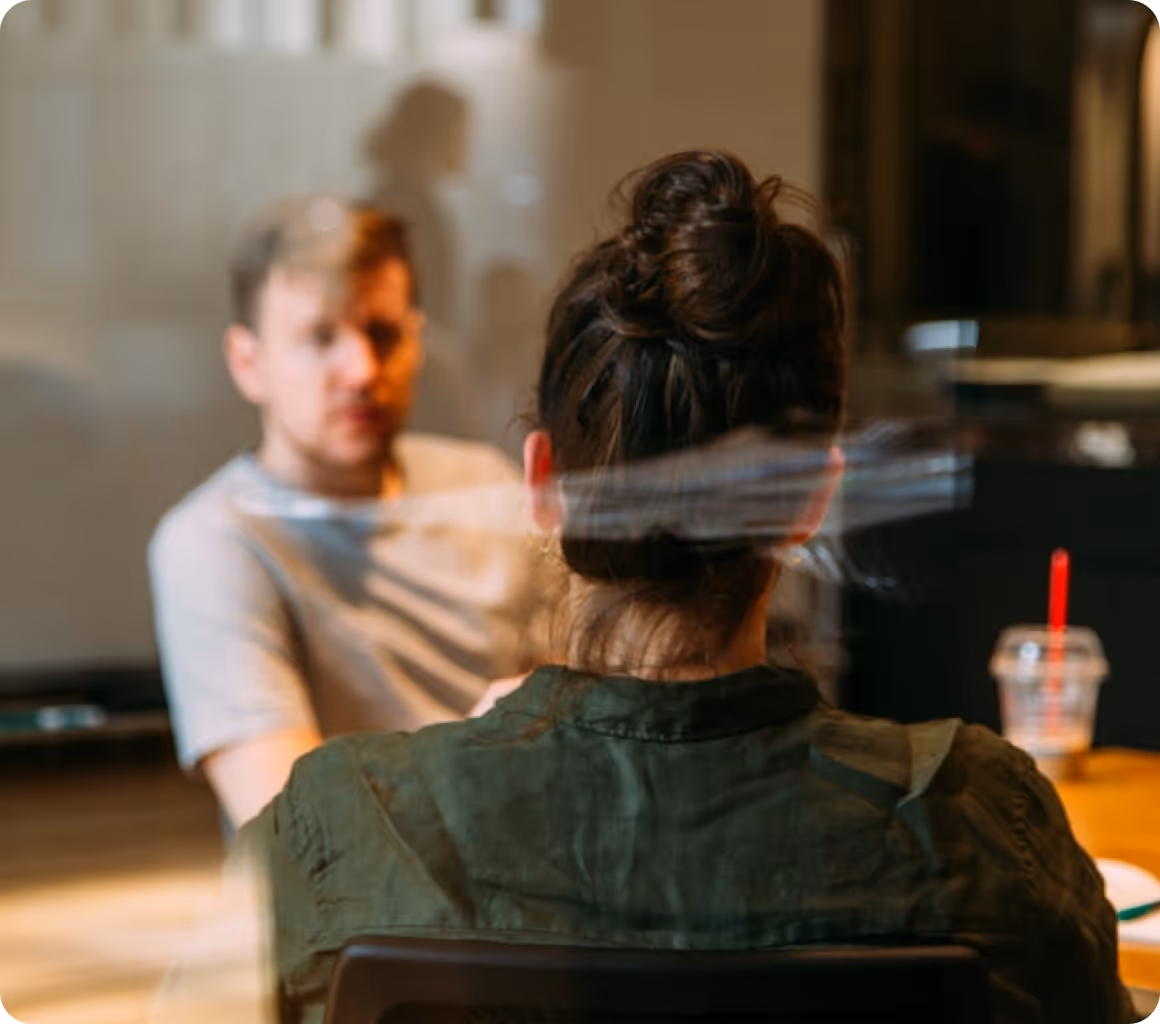 a woman sitting at a table with a man behind her