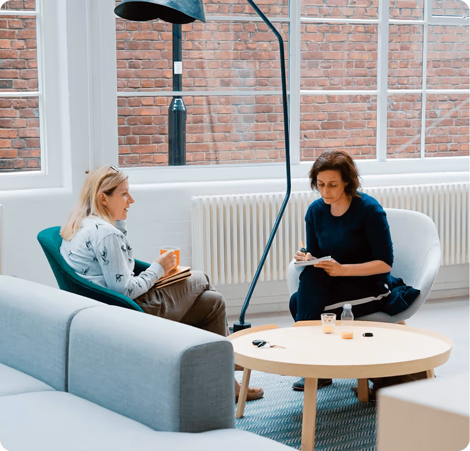 a woman sitting in a chair and writing on a notepad