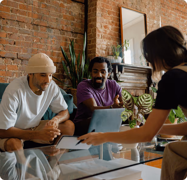 a group of people sitting on a couch and looking at a laptop