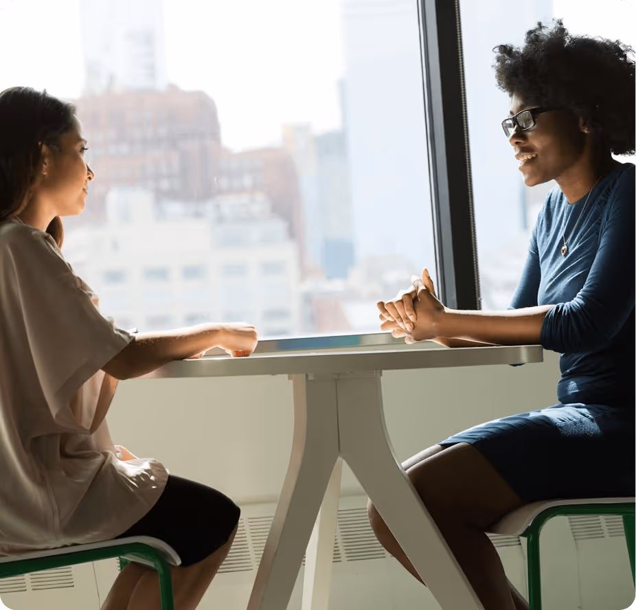a woman sitting at a table with another woman sitting at a table