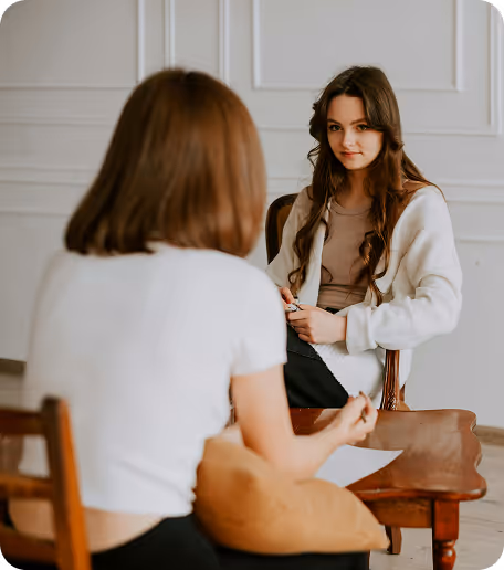 a woman sitting in a chair and looking at another woman