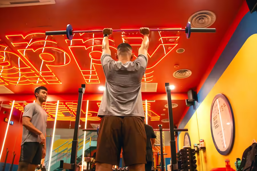 a Good Juju coach cheering on a client doing a barbell overhead press