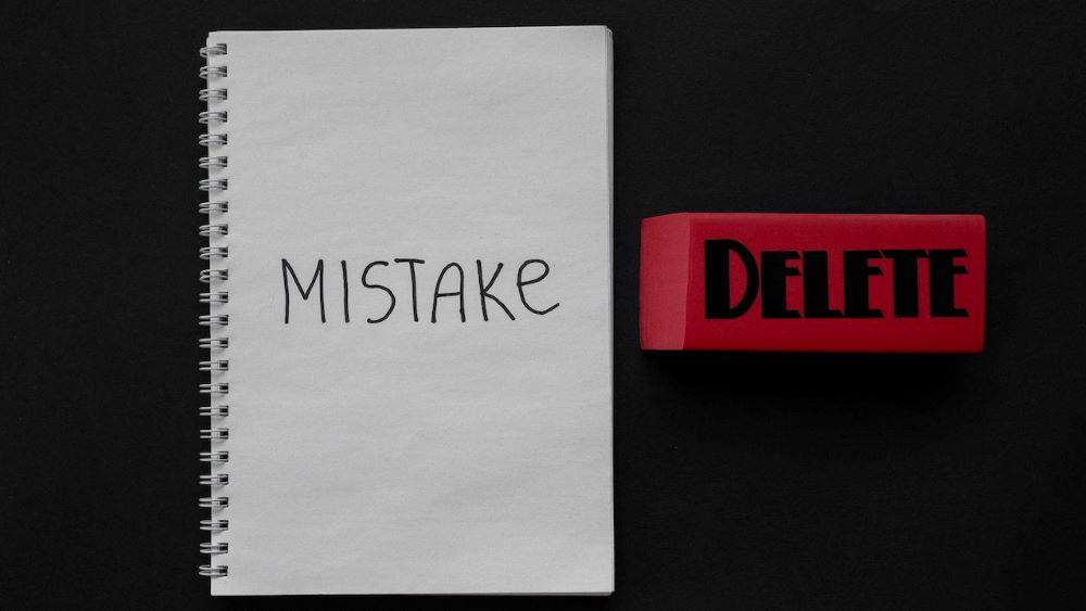 Mistake written on a notebook and delete written on a big, red eraser