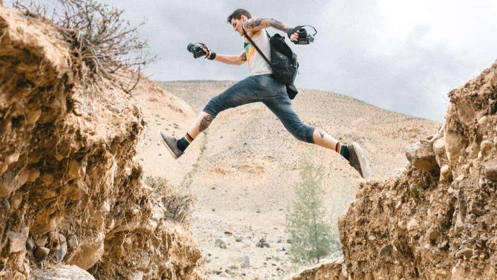 Adventurous man jumping over large pit