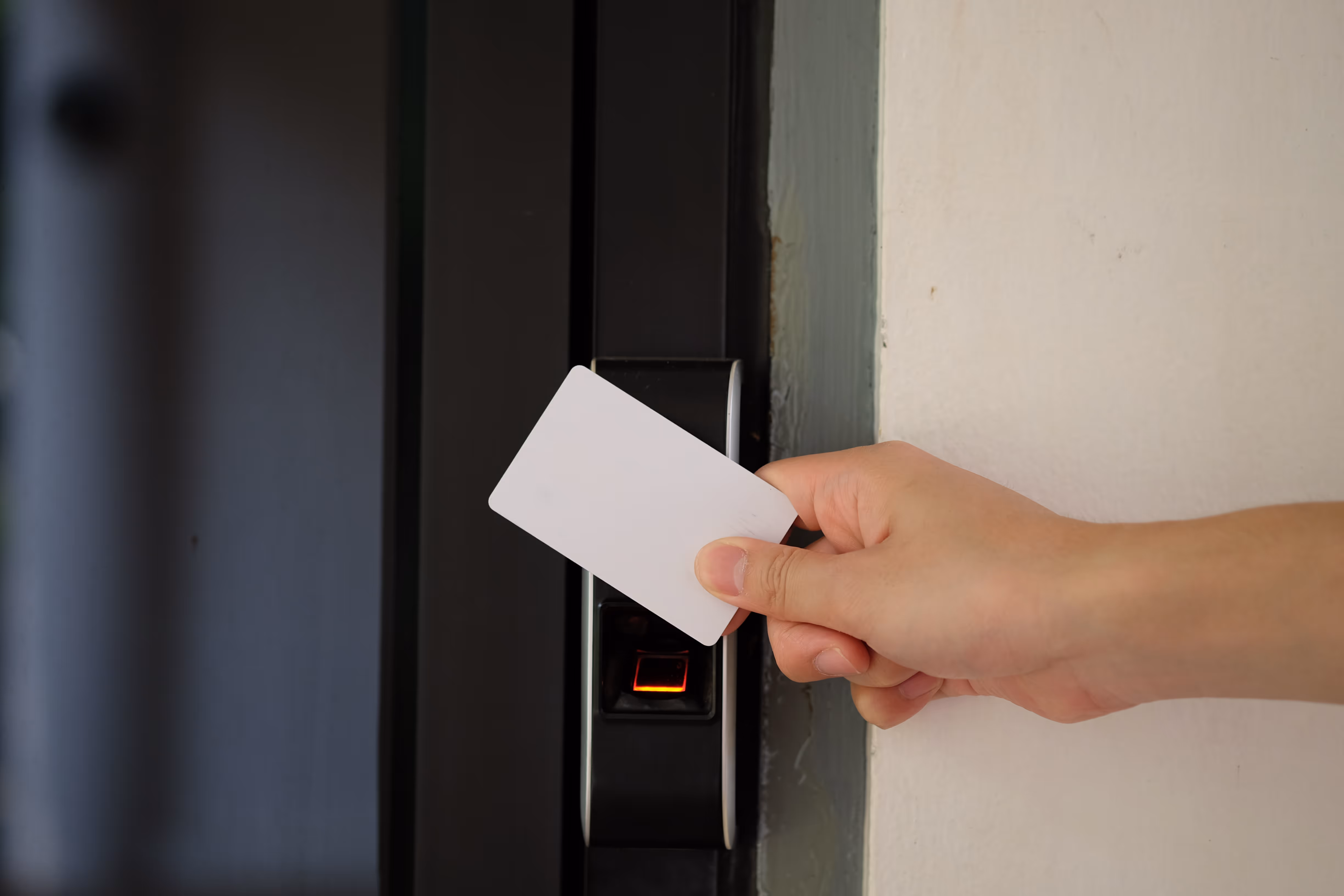 Main tenant une carte d’accès devant un lecteur électronique, illustration d’un système de contrôle d’accès sécurisé à Bordeaux.