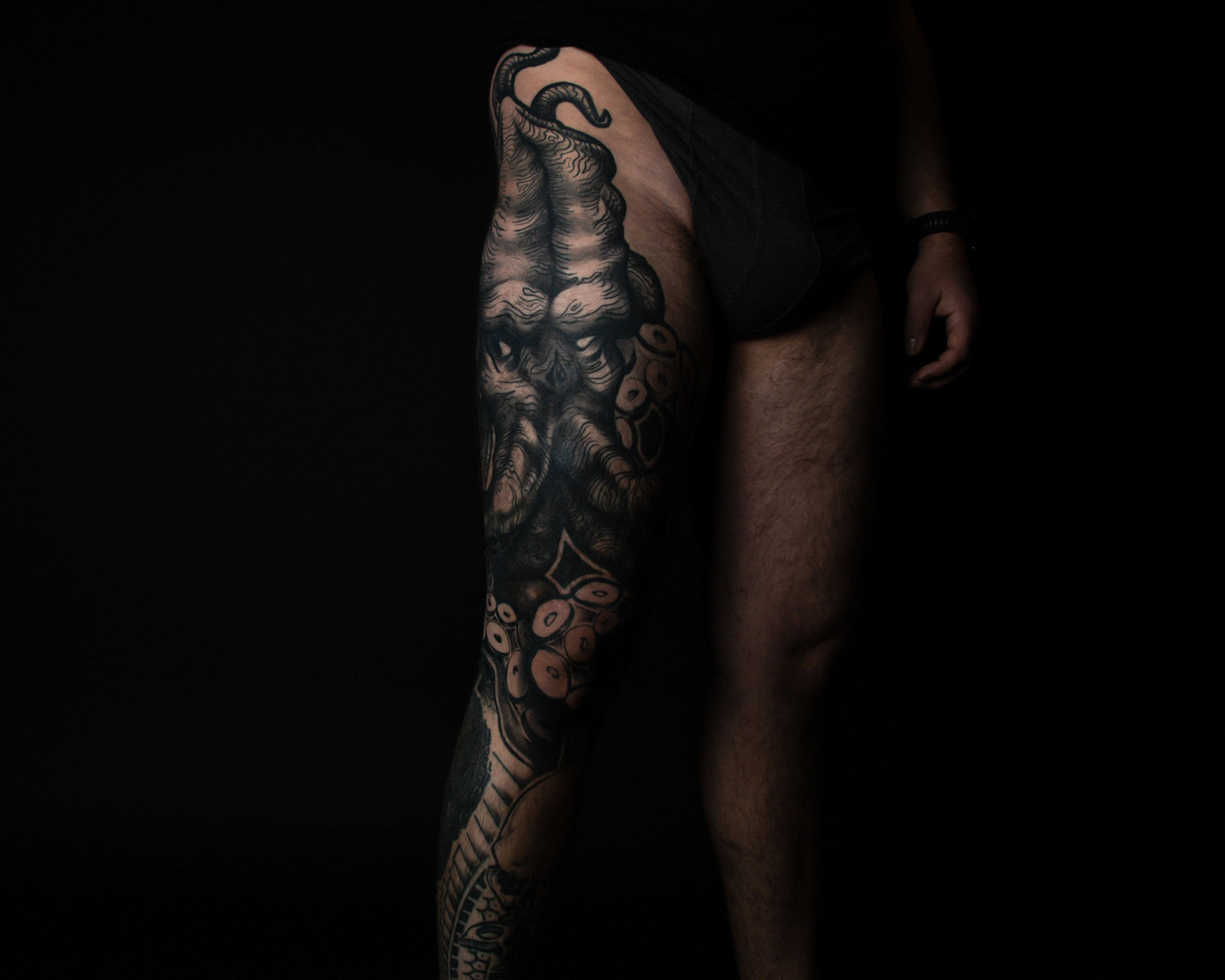 Oberschenkel mit einem schwarzen, detaillierten Tattoo eines Oktopus mit Tentakeln.