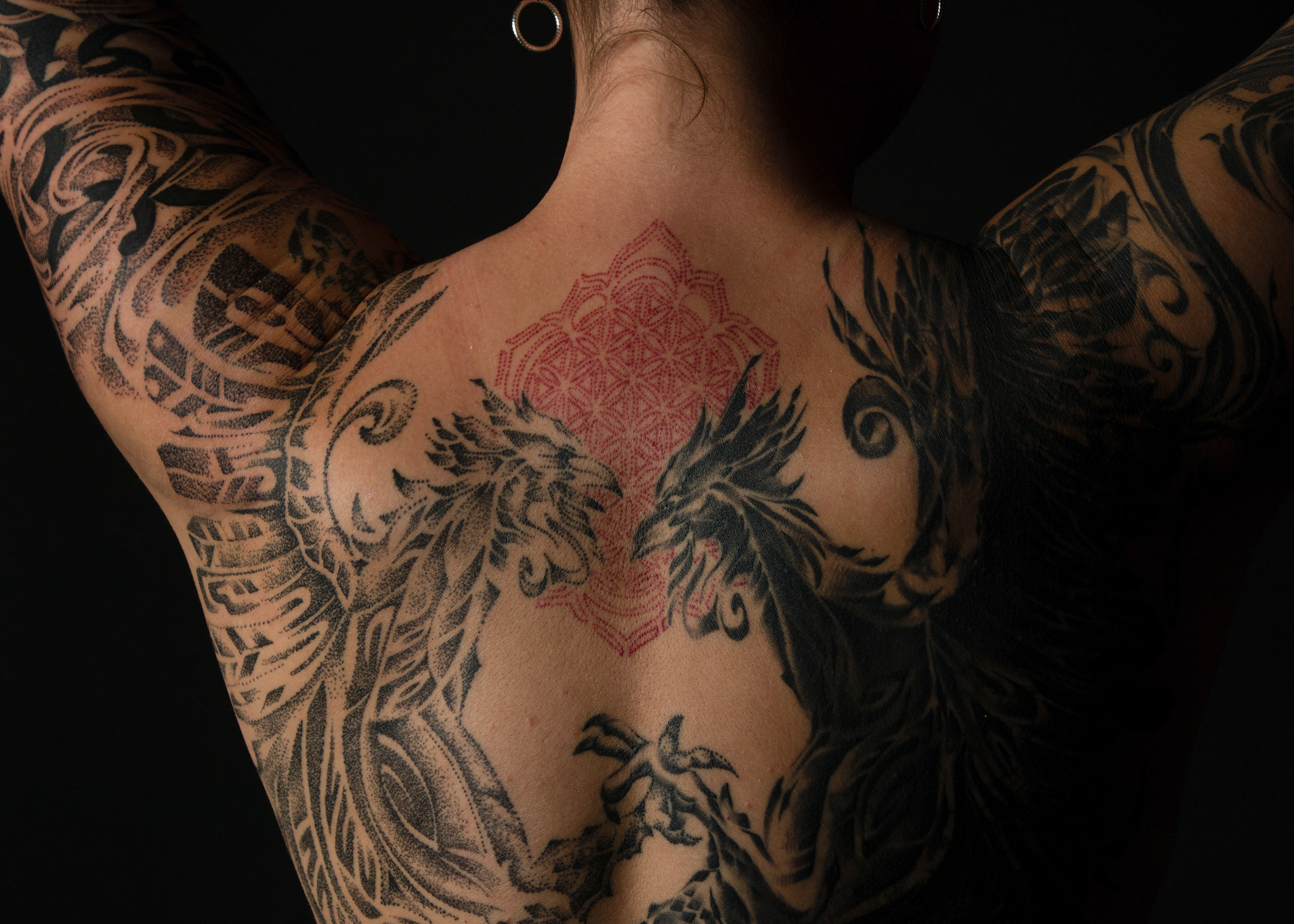 Bold and intricate black tattoo featuring a majestic crow perched on a leafless tree branch, evoking a sense of mystery and symbolism