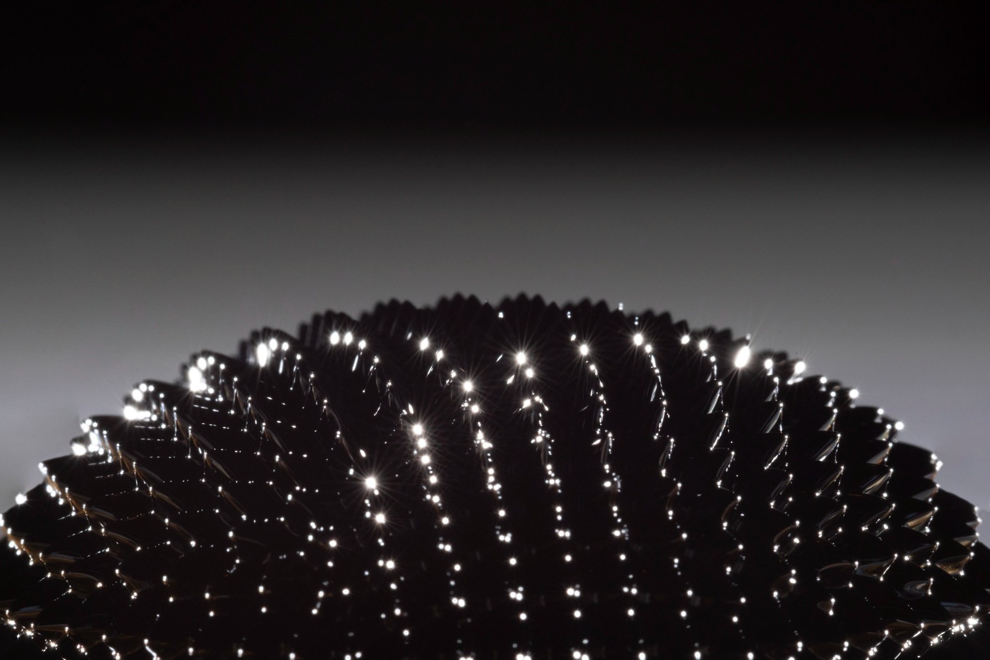 Nahaufnahme eines reflektierenden metallischen Objekts mit Lichtpunkten – symbolisiert ruhiges Design ohne flackernde Animationen.