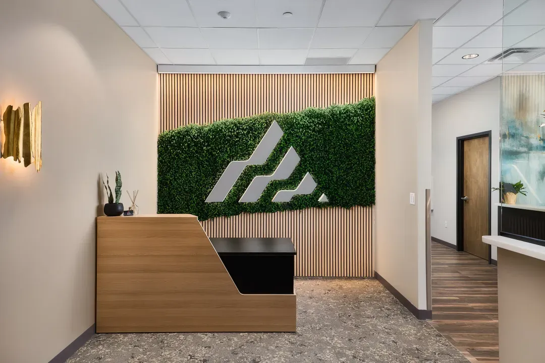Branded reception desk with logo green wall, an example of commercial interior design