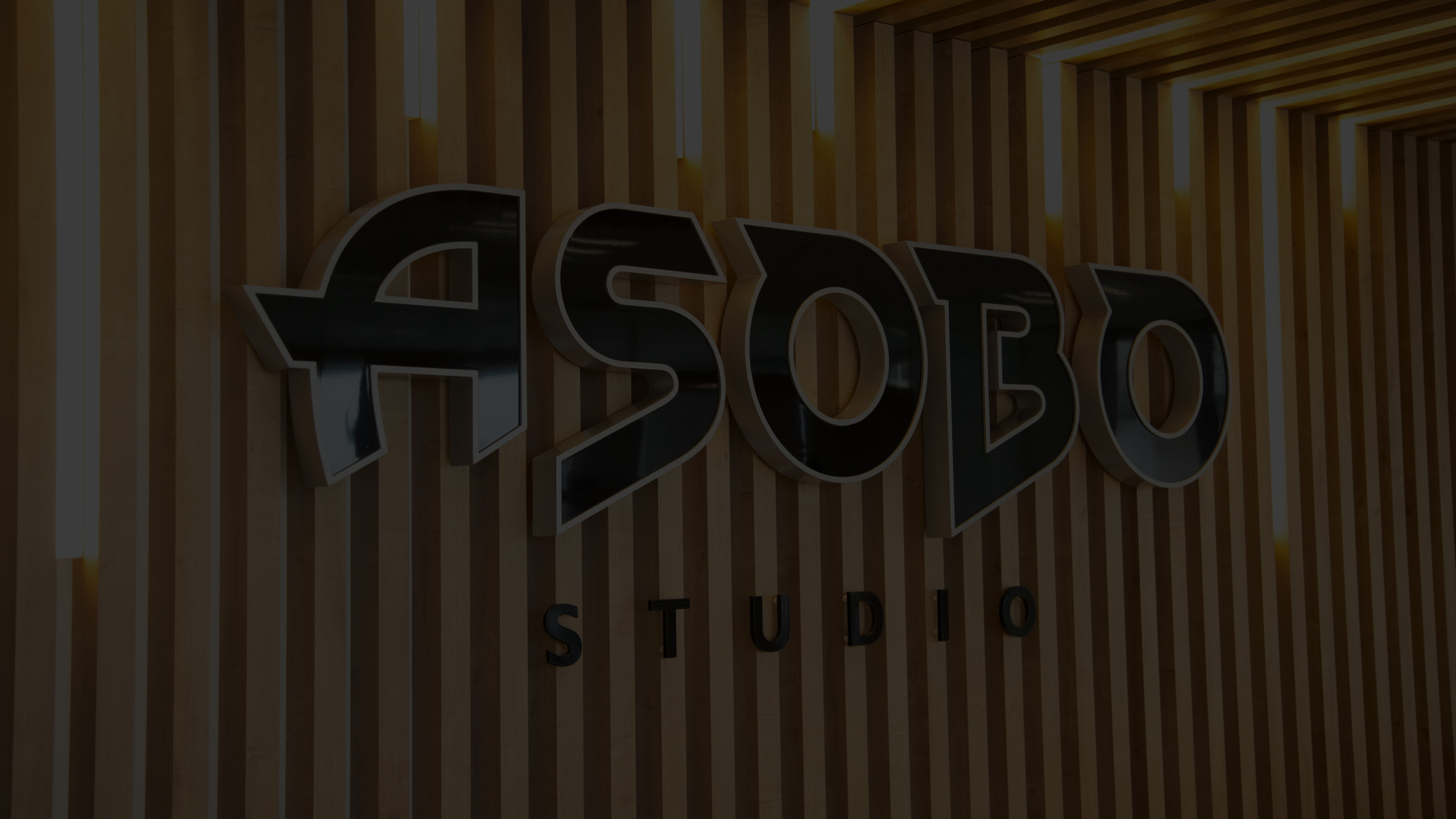 Accueil moderne des bureaux d’Asobo Studio avec comptoir blanc, plafond en bois et salle vitrée attenante