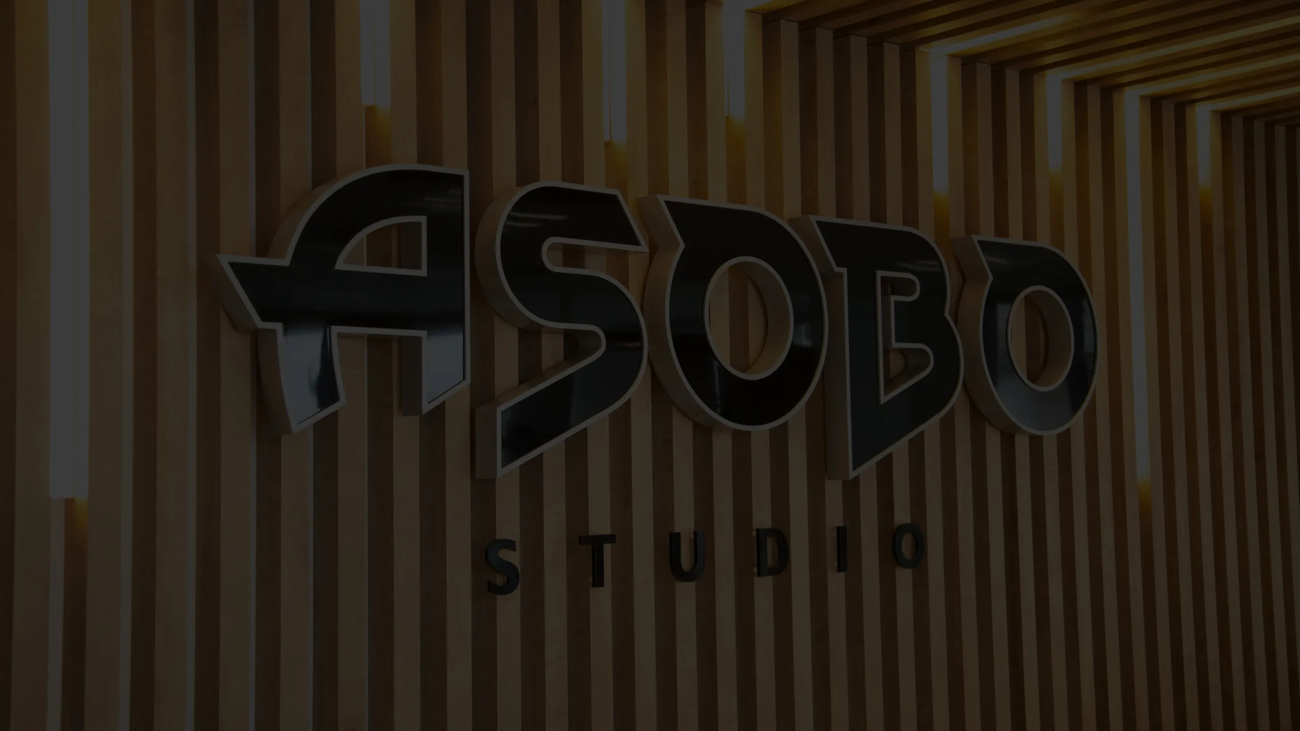 Accueil moderne des bureaux d’Asobo Studio avec comptoir blanc, plafond en bois et salle vitrée attenante