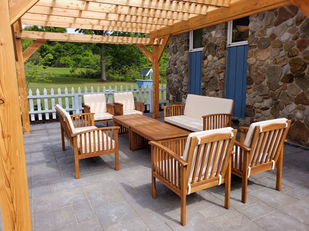 A hardscape patio installed by Pro Snow Removal in Cicero, NY with a wood pergola and porch furniture