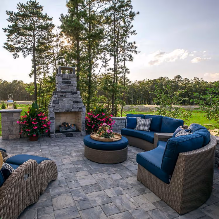 A stone paver patio with blue porch furniture and a custom stone fireplace in LaFayette, NY