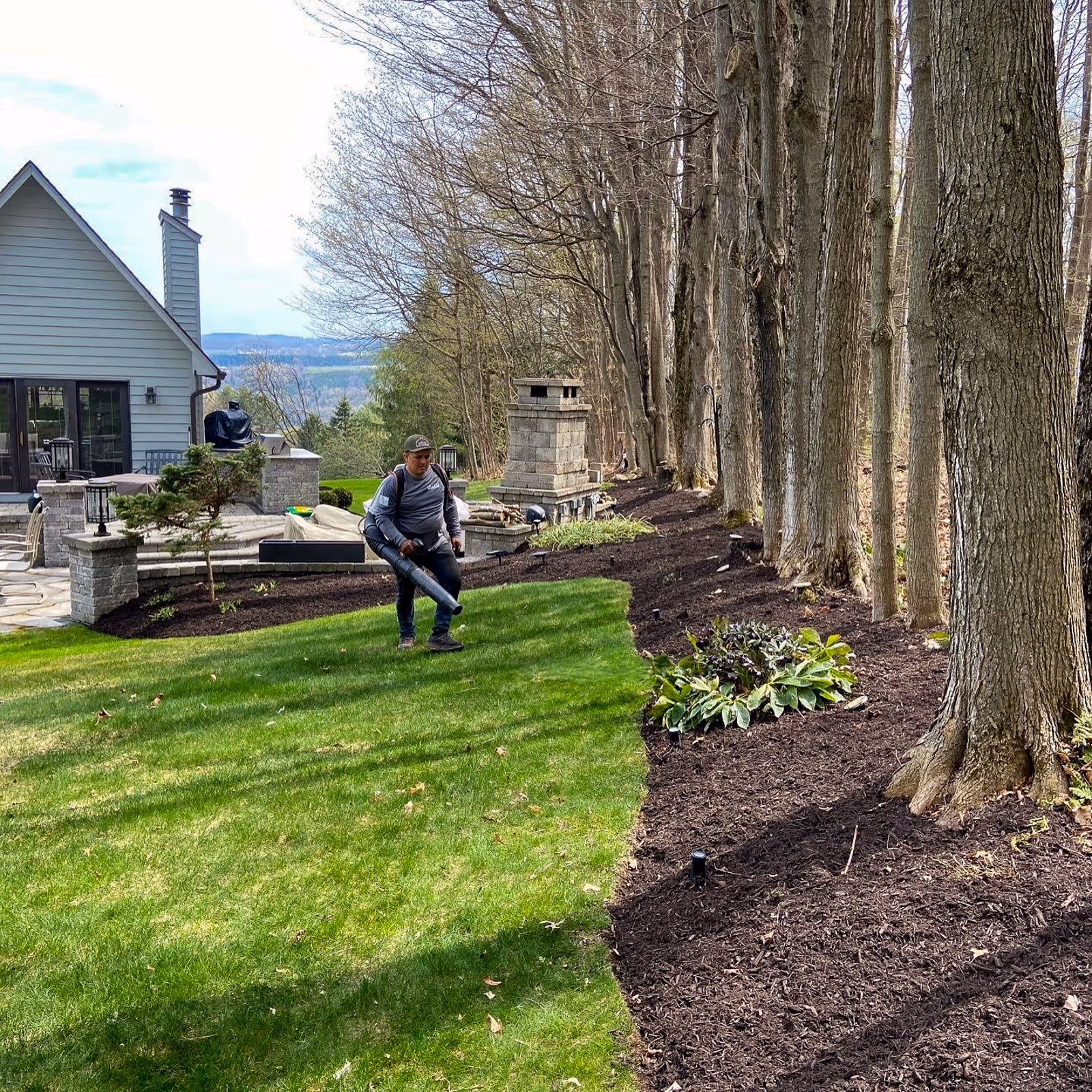 A Pro Snow lawncare employee using a leaf blower on a freshly mowed lawn in Syracuse, NY