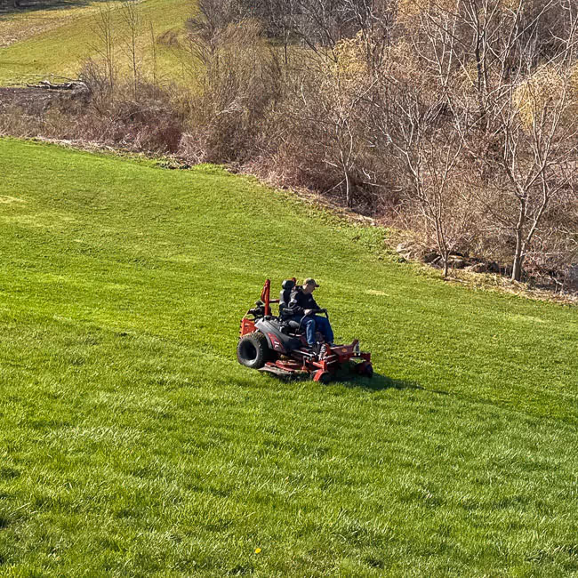 A PSR lawncare employee riding a zero-turn mower in Syracuse, NY