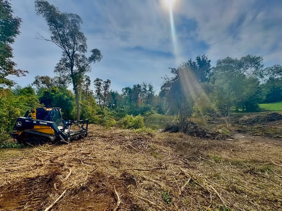 A freshly cleared plot of land with a PSR skidsteer parked beside it