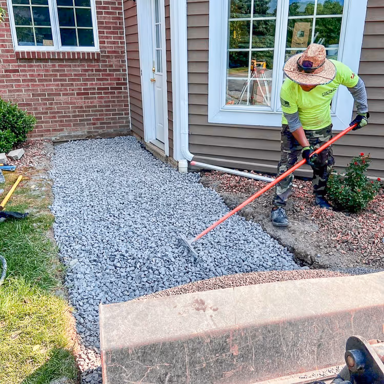 A Pro Snow employee raking stones