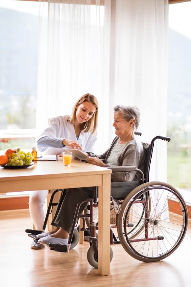 Gerontologist answers elderly woman's questions using tablet