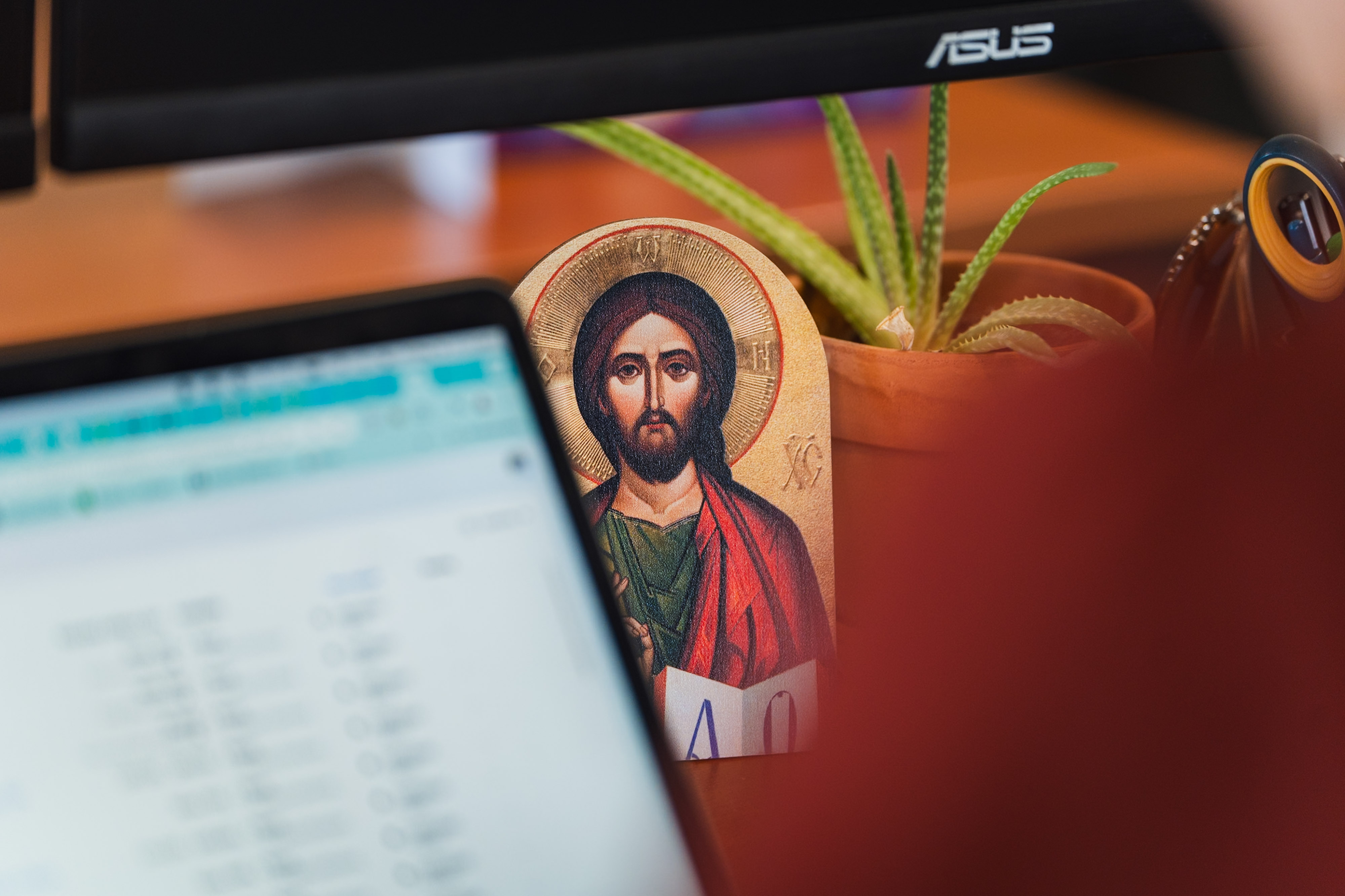 icon of Jesus on a desk with succulent plant and laptop