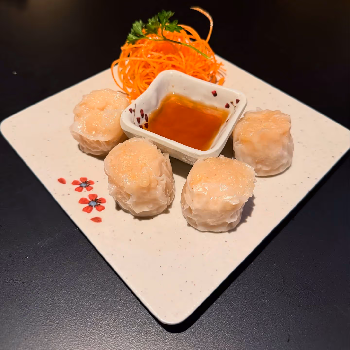 A plate featuring several dumplings accompanied by a small bowl of sauce.