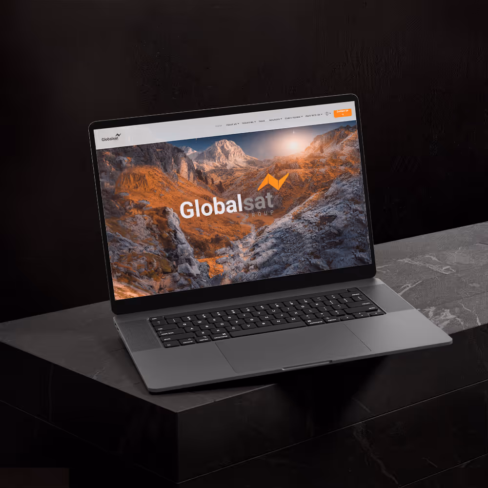 Open laptop on dark marble surface showing GlobalSat Group website with mountain background.