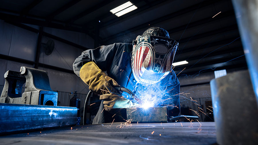 Factory worker welding during production equipment setup for new line transition