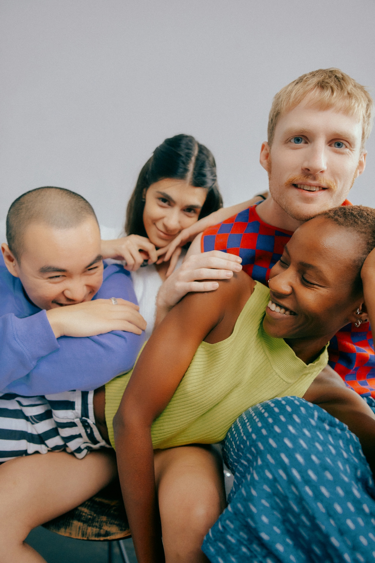 Group of four diverse friends sitting closely together, smiling and enjoying each other's company.