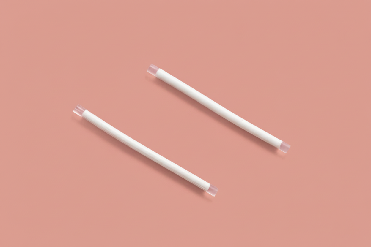 Two white cylindrical rods with transparent square ends on a pink background.