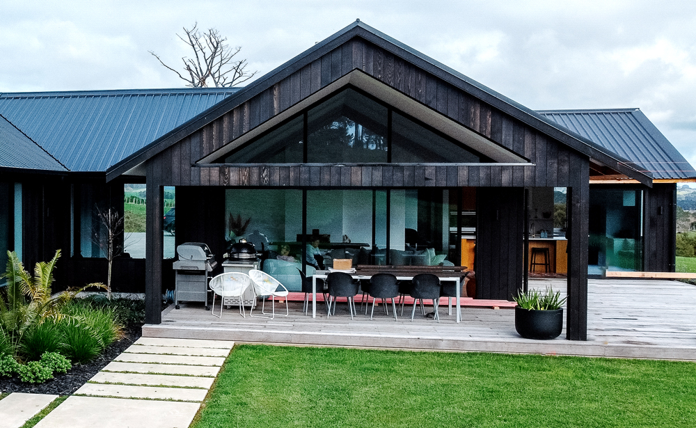 Custom aluminium windows and doors on black-clad modern home in Wellsford with outdoor living area