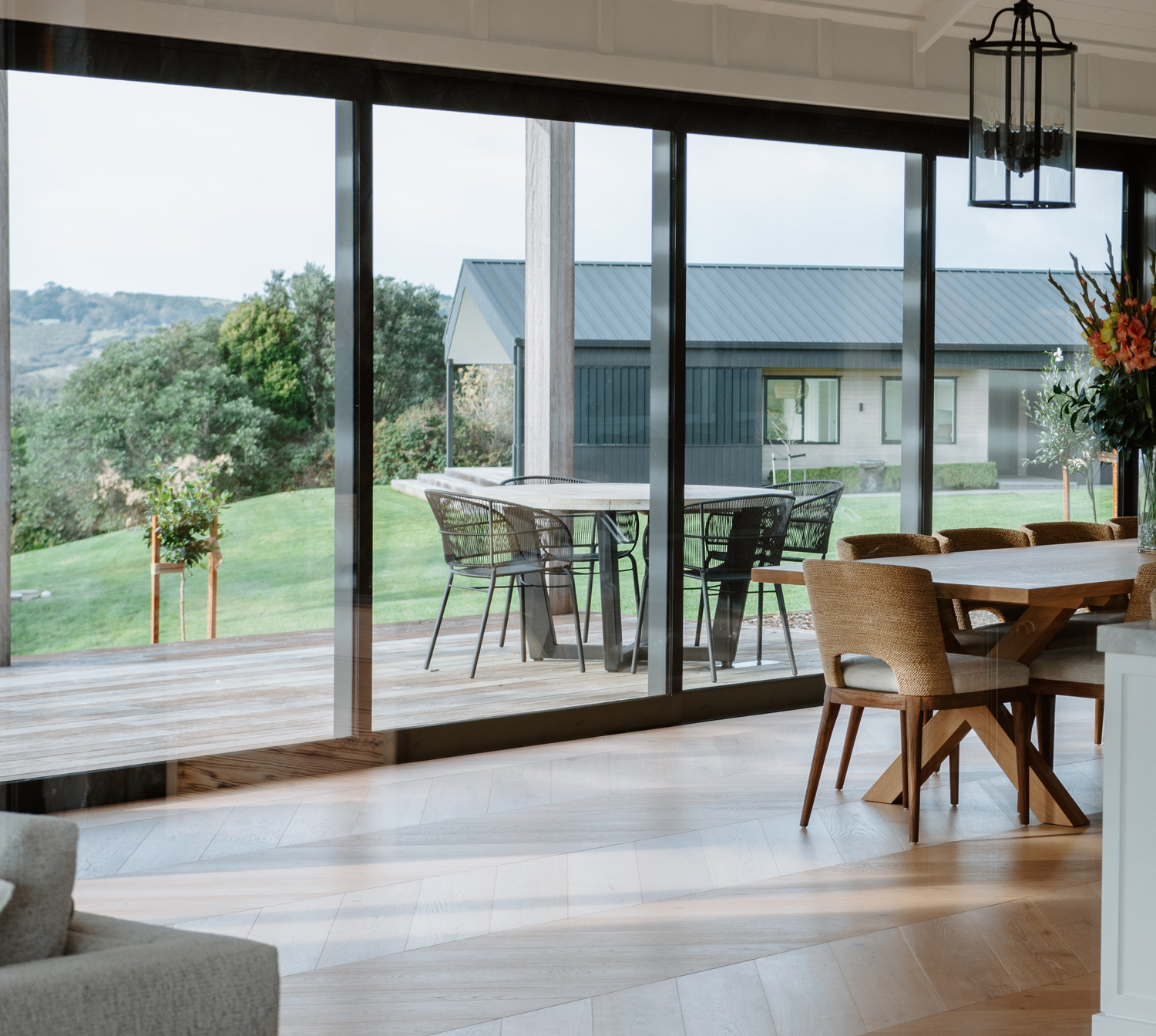 Aluminium sliding glass doors by Rodney Aluminium, showcasing seamless indoor-outdoor flow between a modern dining space and timber deck, with expansive views and clean architectural lines.