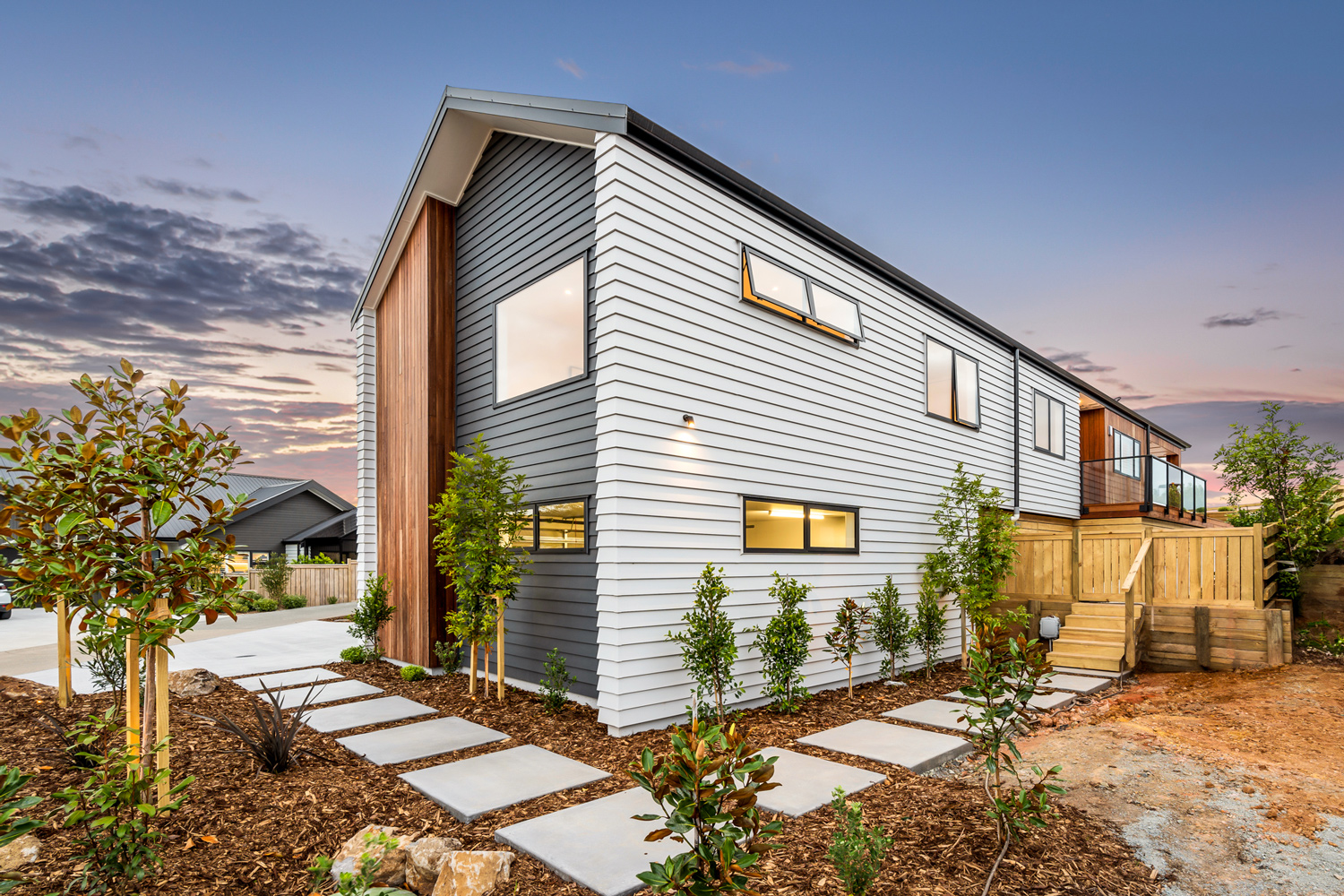 Contemporary home featuring black-framed aluminium windows and doors by Rodney Aluminium, set against light grey cladding with timber accents, located on the Hibiscus Coast.