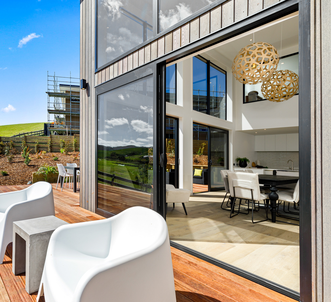 Architectural home in Puhoi featuring full-height aluminium sliding doors and double-glazed windows, opening onto a timber deck with rural views.