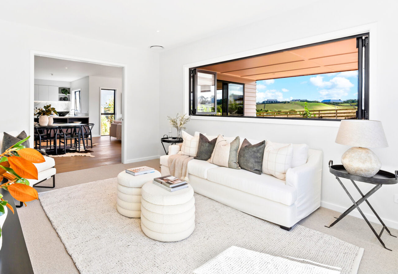 Bright living room featuring aluminum bifold windows opening to a covered outdoor space, showcasing seamless indoor-outdoor flow and modern joinery in a Northland home.
